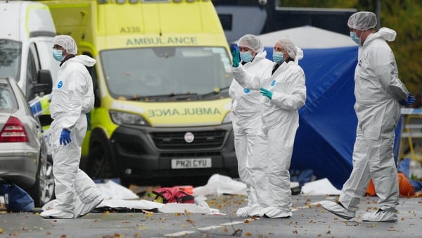 People in white overalls work at a crime scene