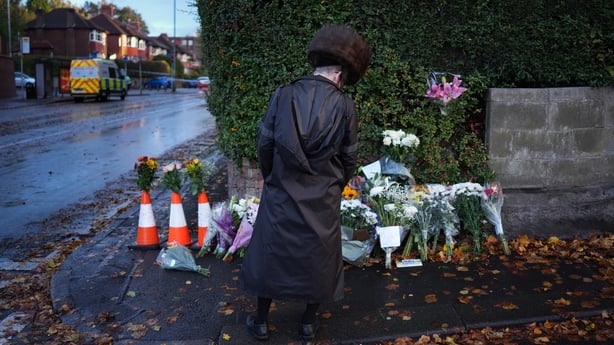A man looks at floral tributes at a police cordon 