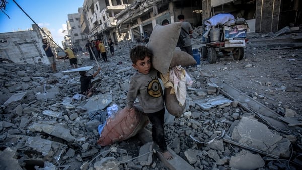 A small boy carries belongings as he walks amid destroyed streets in Gaza