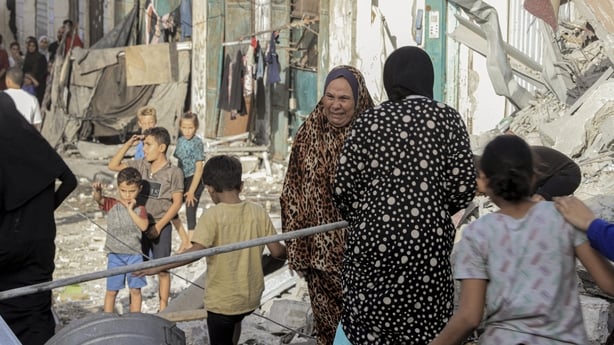 women and children gather in a damaged street in gaza