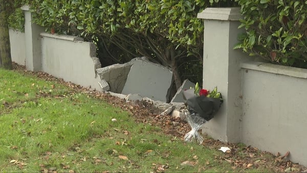 flowers left beside a broken wall and grass after a crash