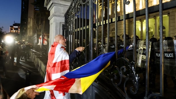 Protesters face riot police as they attempt to break into the grounds of the presidential palace