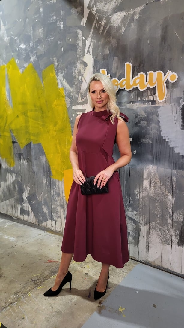 Model wearing a dress and holding a clutch bag