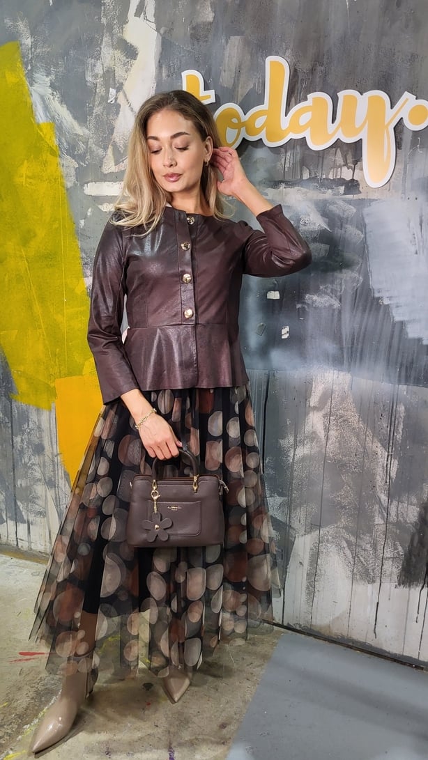 Model wearing a dress and jacket and holding a handbag