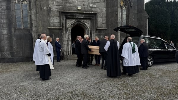 Mourners carry the coffin of Martin Mansergh into the church