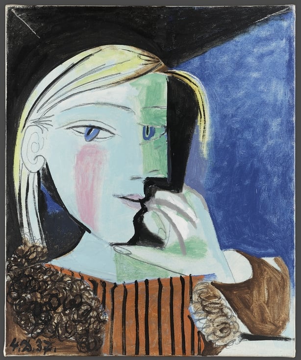 A Picasso painting of a woman with blonde hair wearing an orange and black vertical striped blouse against a blue background