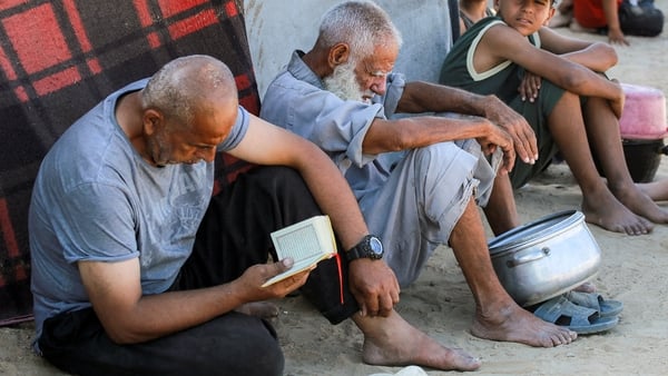 People sit outside a tent sheltering people displaced by war in Deir el-Balah in Gaza