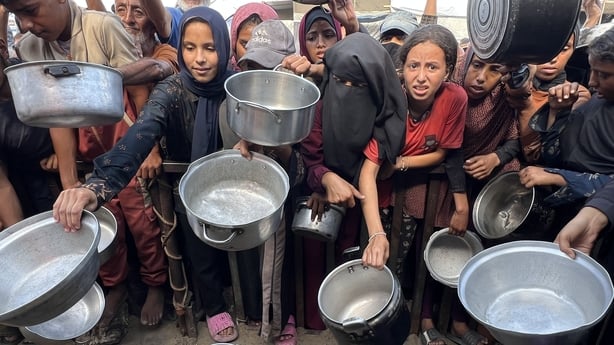 Palestinians wait with their empty pots to receive hot meals - (Photo by Abed Rahim Khatib/Anadolu via Getty Images)