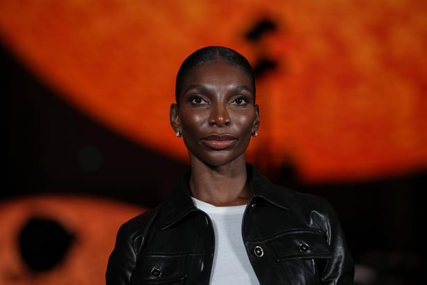 Michaela Coel poses for a photo in front of a large globe shaped like the sun