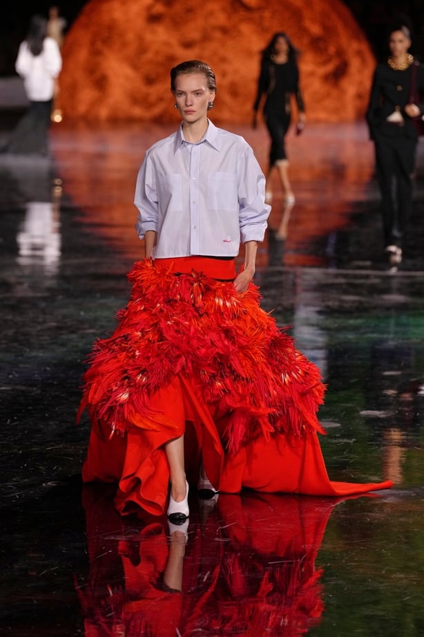 A model wearing a blue shirt and a red skirt on the Chanel runway