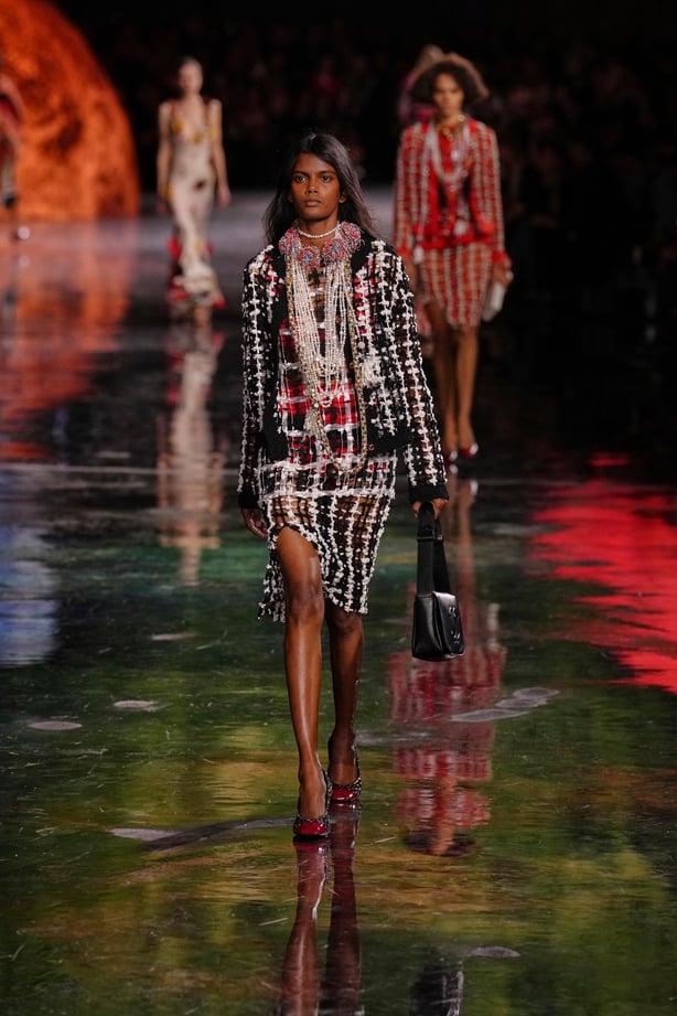 A model wearing a tweed suit walks the runway at Chanel's show