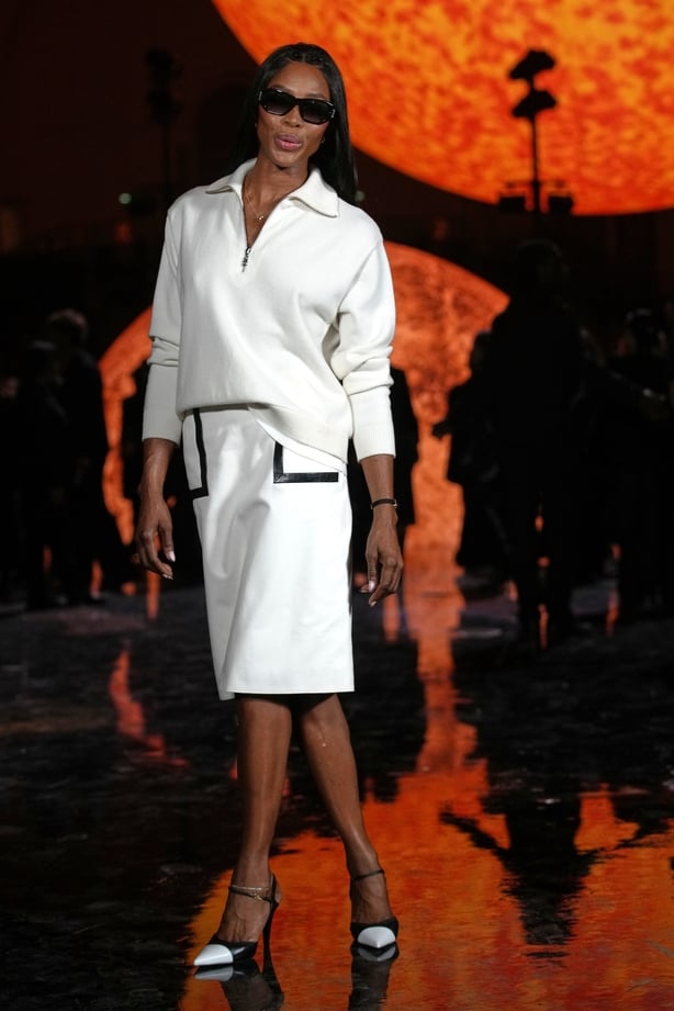 Naomi Campbell poses for a photo in front of a large globe shaped like the sun
