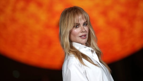 Nicole Kidman poses for a photo in front of a large globe shaped like the sun