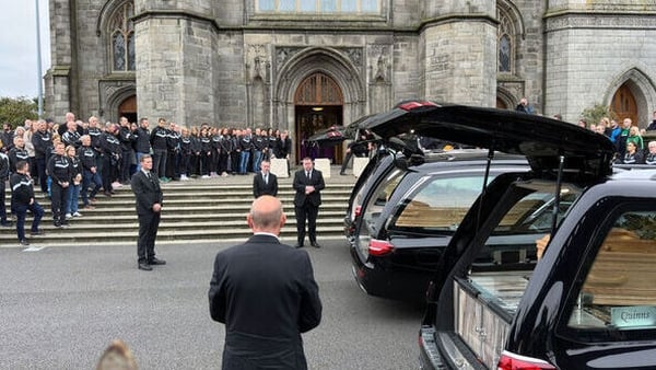 Funeral car with mourners gathered outside church