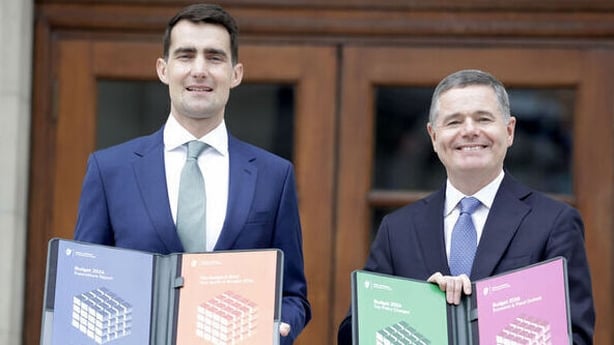 Jack Chambers and Paschal Donohoe holding colourful folders outside Government Buildings