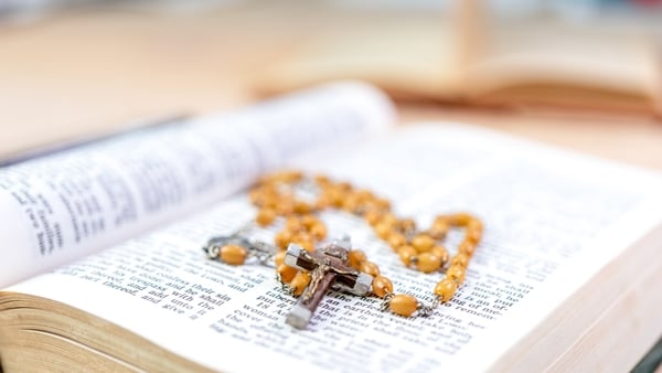 Closeup of wooden rosary beads on top of an open bible