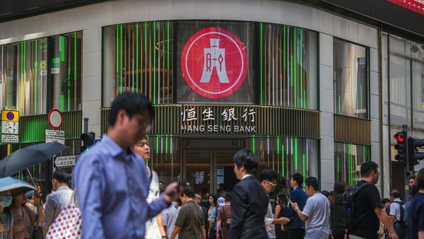 People on a busy street walk outside a Hang Seng Bank branch in Hong Kong