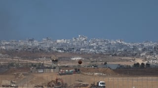An Israeli military armoured vehicle is transported on the back of a truck along the Israel-Gaza