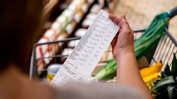 Close-up on a woman looking at a receipt after shopping at the supermarket - cost of living concepts