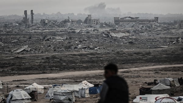 A man is seen looking across a charred landscape in gaza