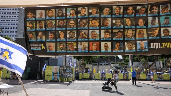 People in tel aviv walk past posters of hostages held in gaza