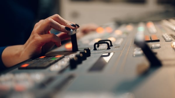 Woman using equipment in control room for television production.
