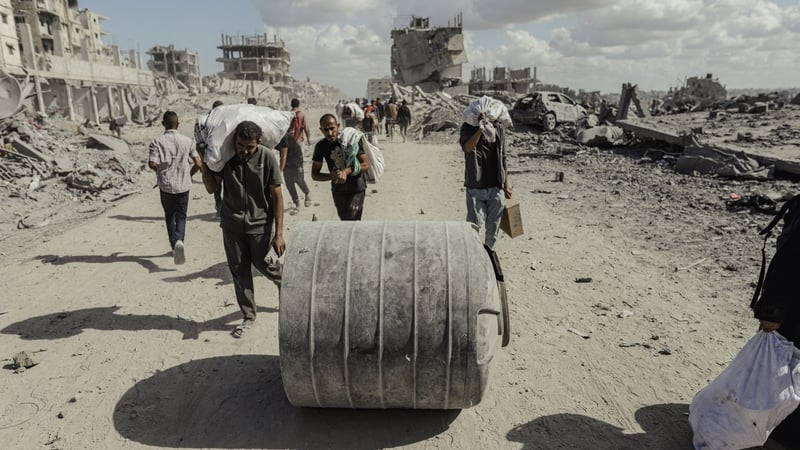 Palestinians walk along a street amid rubble in the Al-Jalaa area