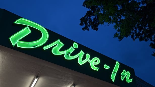 A neon drive-in sign at dusk