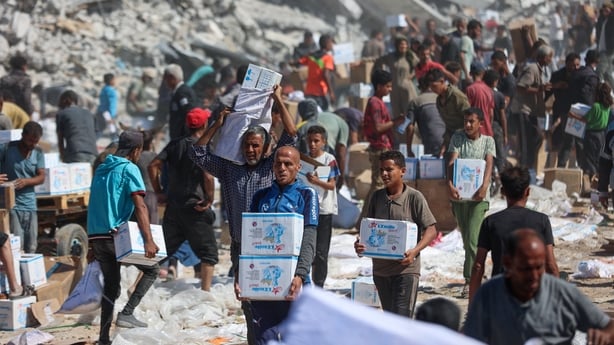 Palestinians receive food parcels after aid trucks entered from the Karem Abu Salem crossing
