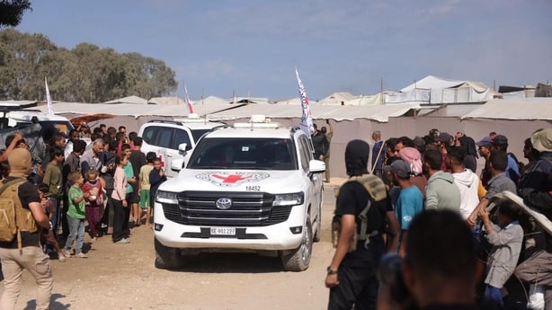 Palestinians gather on the sides of the road as International Red Cross vehicles arrive to transport the second batch of released Israeli hostages