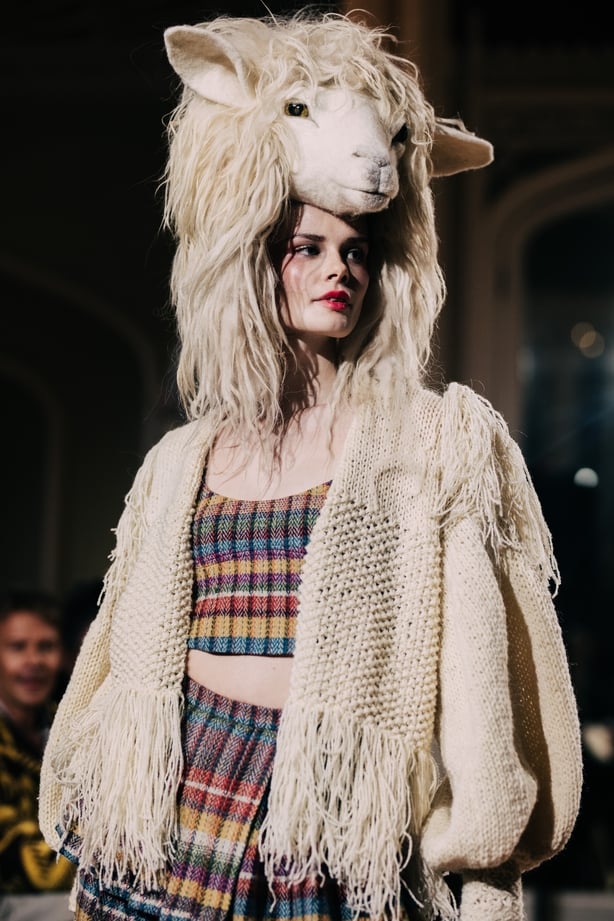 A model wearing a knitted top and skirt and a headdress in the shape of a sheep