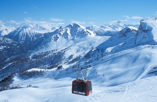 A cable car passing by snowy mountains