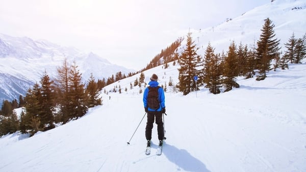 A person looking over snowy mountains while skiing