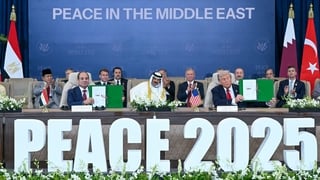 Several men sit at a long table. Two are holding up documents in green folders. The words 'Peace 2025' are written on the front of the table.