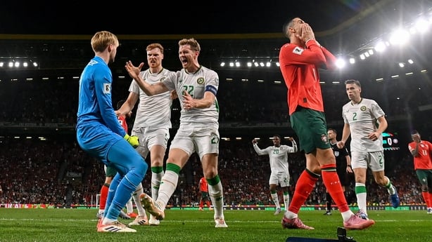 11 October 2025; Republic of Ireland goalkeeper Caoimhin Kelleher celebrates with teammates Nathan Collins, right, and Jake O'Brien, centre, after saving the penalty of Cristiano Ronaldo of Portugal during the FIFA World Cup 2026 Group F qualifying match between Portugal and Republic of Ireland at E