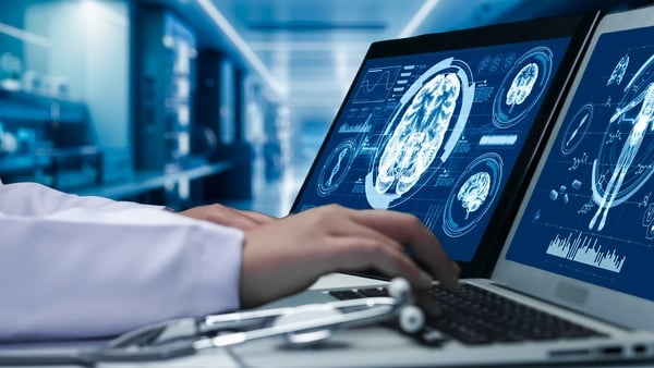 Close up of doctor working on tablet and laptop with human brain anatomy display on screen