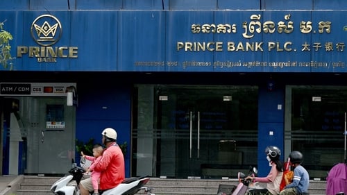 Motorists ride past a branch of the Prince Bank in Phnom Penh