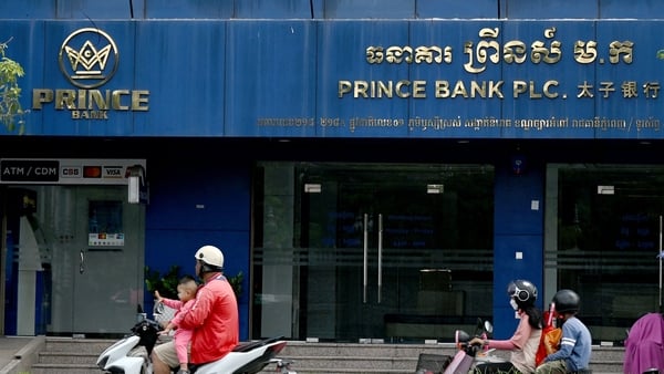 Motorists ride past a branch of the Prince Bank in Phnom Penh