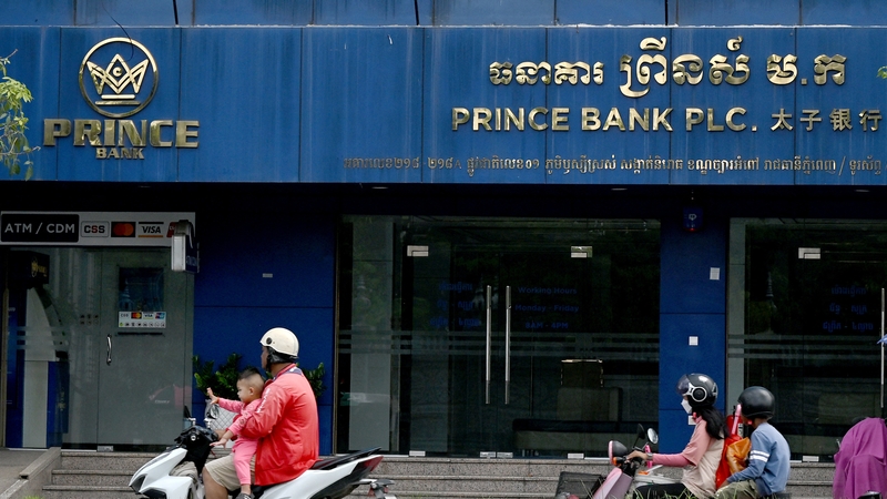 Motorists ride past a branch of the Prince Bank in Phnom Penh