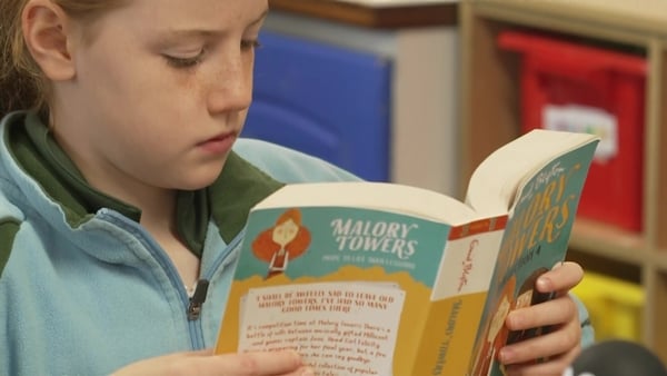 A girl at school reading the book Mallory Towers