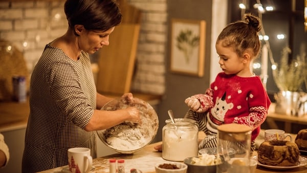 Mother with children in kitchen preparing Christmas cakes