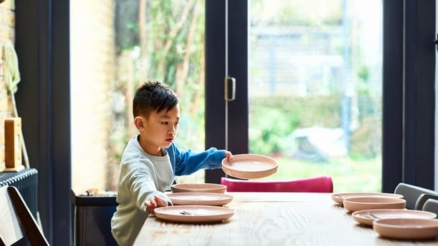 Young Chinese boy putting plates on dining table, a helping hand, domestic life, arranging