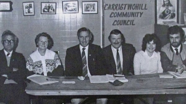 Six people sit at a desk with a sign carrigtwohill community council behind them