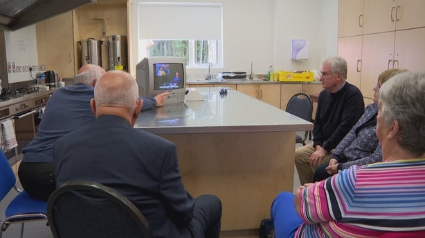 A screengrab from Nationwide showing people sitting around a desk watching a television