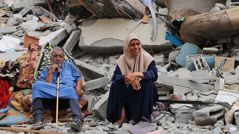 An elderly couple grieves in front of their destroyed home in Gaza City