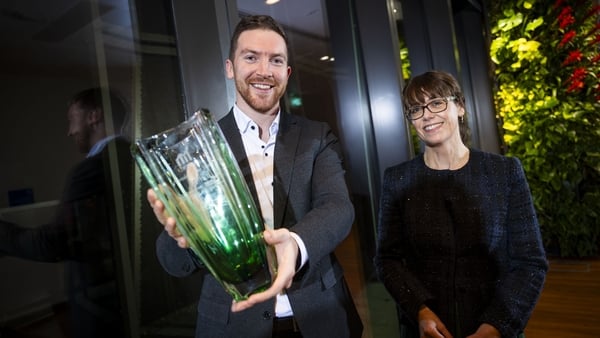 Image of a man holding an enterprise award standing beside a woman