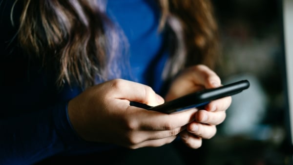 A focused view of individual's hands using a mobile phone indoors
