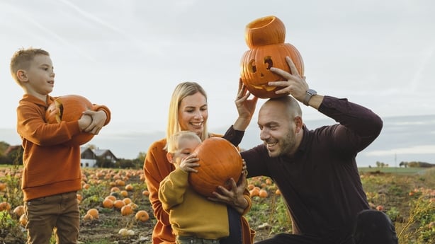 Happy parents with sons carrying jack o' lanterns at pumpkin patch