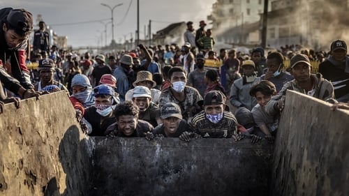 A group of people from the so-called 'Generation Z' push a metal container to use as a barricade during clashes in Madagacar