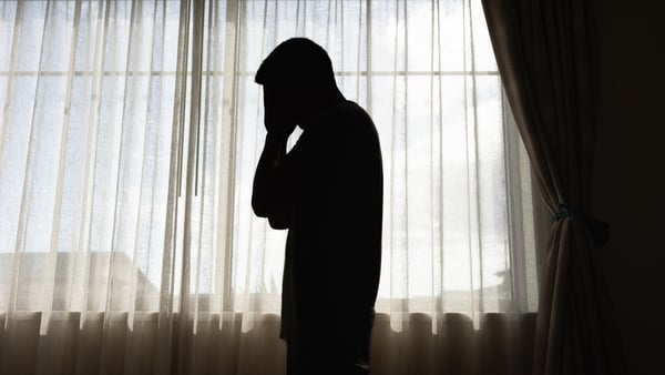 A man holding his head in the shadows